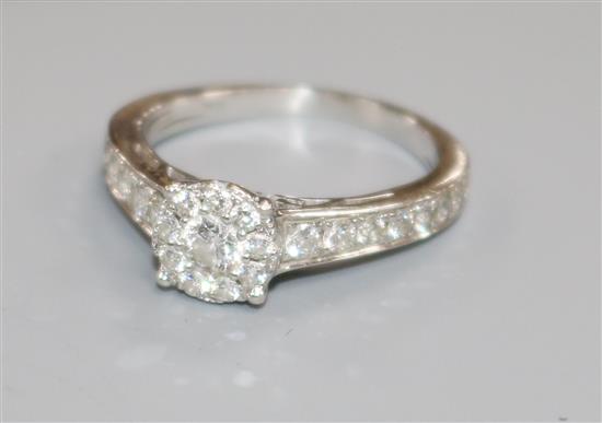A modern white metal and diamond cluster ring with diamond set shoulders, size I.